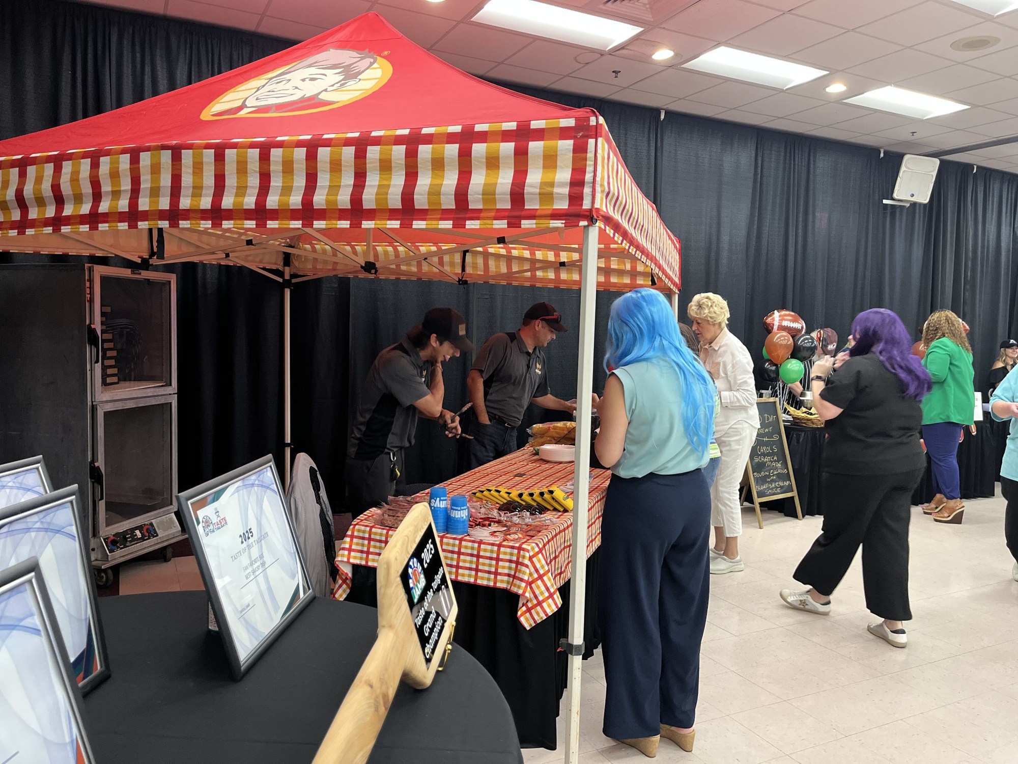Staff and visitors at a sponsor booth during Taste of Tailgate